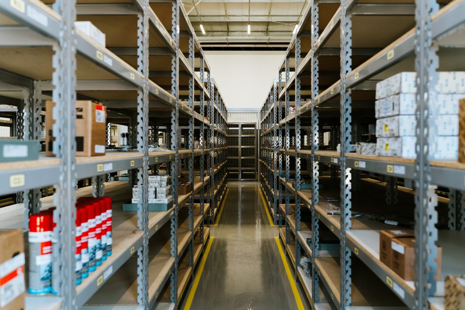 Wide view of an organized industrial warehouse with metal shelving and stored merchandise.